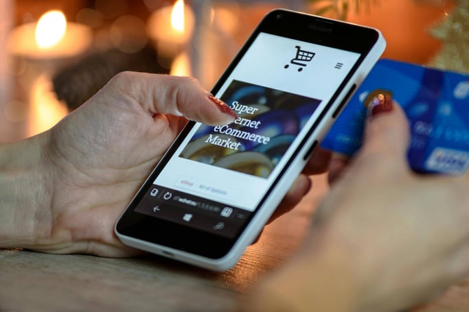 Person typing on a phone with a bank card on the side